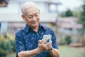 feliz ásia mais velho homem usando Smartphone. foto