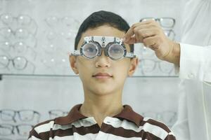 jovem Garoto examinando visão dentro ótico clínica. foto
