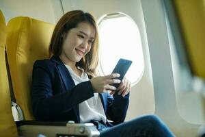 o negócio mulher dentro uma avião, trabalho em usando em telefone. foto