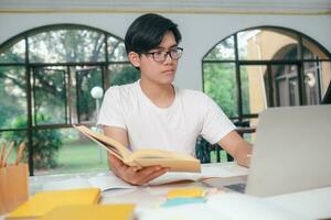 jovem ásia masculino aluna é preparando para lendo uma livros para exames às universidade. foto