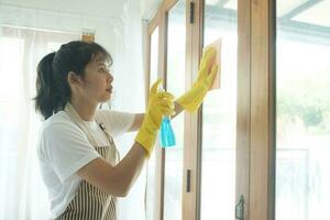 jovem ásia mulher limpeza janela. foto