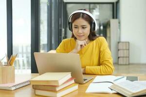 jovem mulher estudando ou trabalhando conectados usando computador portátil e vestindo fones de ouvido. foto
