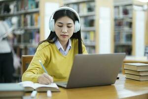 aluna estudando às biblioteca com computador portátil. foto