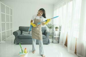 jovem mulher tendo Diversão enquanto limpeza às lar. foto