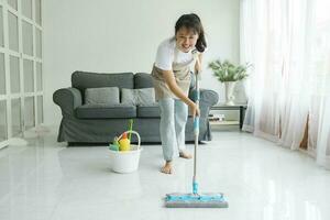 jovem mulher limpeza chão usando esfregão às lar. foto