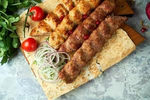 pratos de carne com churrasco e kebab em fundo cinza