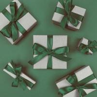 caixas de presente embrulhadas em papel artesanal com fitas verdes e laços festivos monocromáticos plana lay