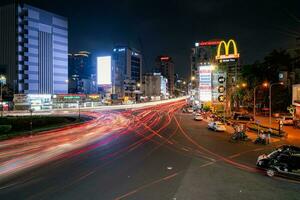 ho chi minh cidade, Vietnã - abril 14, 2023 tráfego geléia às morreu bem phu rotunda com Está quatro caras relógio torre uma símbolo do ho chi minh cidade. luz trilha a partir de carros. foto