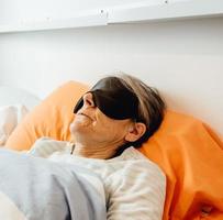 uma senhora dormindo usando uma máscara facial em um quarto moderno