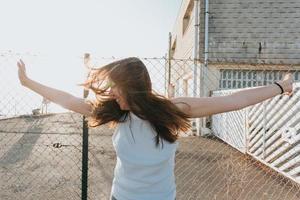 jovem mulher com cabelo comprido movendo seu cabelo durante um pôr do sol com o conceito de liberdade e liberdade e saúde mental com espaço de cópia foto