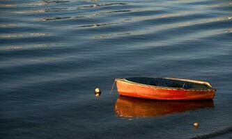 pequeno laranja barco ancorado em a costa foto