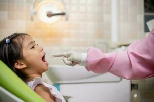 amigáveis jovem dentista examinando feliz criança dentes dentro dental clínica. odontologia conceito. foto