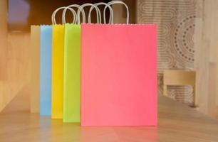 sacolas de papel coloridas em mesas de madeira para mulheres conceito de moda e compras foto
