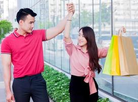 Jovem casal asiático comprando em sacos de papel para as férias foto