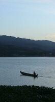 silhueta de pescador em seu barco foto