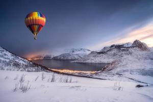 balão de ar quente voando na colina de neve com a cidade de fordgard no inverno foto
