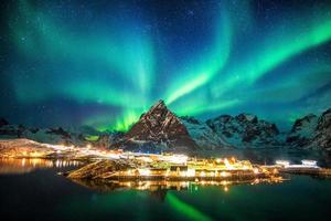 aurora boreal sobre montanhas em vila de pescadores foto