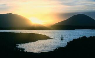 lindo pôr do sol beira do lago panorama cenário com lago e montanhas às connemara nacional parque dentro município galway, Irlanda foto