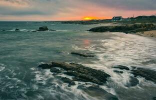 dramático nublado pôr do sol cenário do rochoso às selvagem atlântico caminho, algas marinhas de praia dentro município galway, Irlanda foto