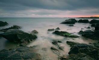 dramático nublado pôr do sol marinha cenário do rochoso costa às selvagem atlântico caminho, algas marinhas de praia dentro município galway, Irlanda foto