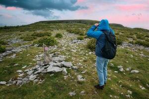 lindo nascer do sol panorama cenário com homem caminhada em topo do a montanha dentro azul Jaqueta e mochila às Burren nacional parque dentro município Clara, Irlanda foto