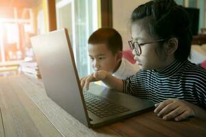 dois ásia crianças Aprendendo para usar computador computador portátil às casa vivo quarto foto