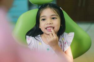 fechar acima retrato do uma caucasiano menina tendo a exame às a pediatra dentista enquanto sorridente às Câmera foto