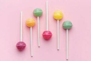 pirulitos doces no fundo rosa foto