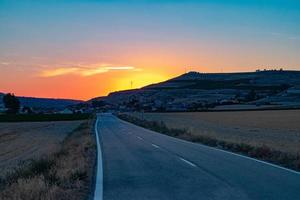 estrada vazia cruzando campo agrícola ao pôr do sol