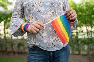 senhora asiática segurando o símbolo da bandeira da cor do arco-íris do mês do orgulho lgbt comemorar anual em junho social de direitos humanos lésbicas bissexuais transgêneros foto