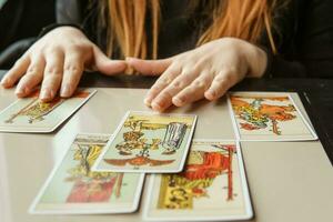 tver, Rússia - fevereiro 11, 2023. tarot cartões, tarot cartão adivinhação, esotérico fundo. uma mulher faz uma disposição em a cartões às a mesa. adivinhação, previsões em tarot cartões. foto