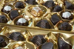 chocolate doces do vários formas dentro uma brilhante dourado pacote. foto