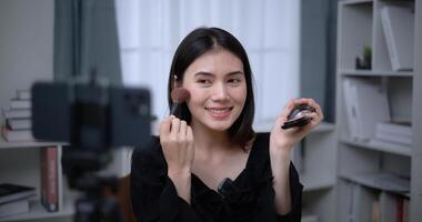 lindo jovem ásia mulher blogueiro mostra quão para faço acima cosméticos às casa foto