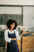 comece bem sucedido pequeno o negócio proprietário sme africano mulher ficar de pé com tábua dentro cafeteria restaurante. mulher barista cafeteria proprietário. foto