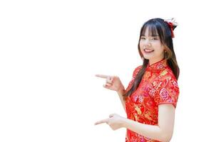 cheongsam vestir dentro chinês Novo ano tema enquanto dela mão mostra para ponto presente alguma coisa e parece às Câmera sorridente alegremente com isolado em branco fundo foto