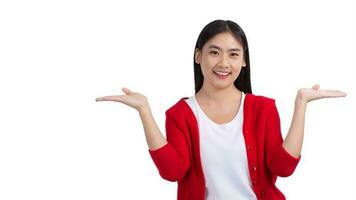 ásia fofa menina dentro branco camiseta e vermelho camisa sorridente e mostrando mão para presente alguma coisa isolado em branco fundo. foto
