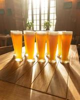 muitas canecas de cerveja na mesa com o sol brilhando pela janela de vidro foto