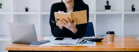 mulher de negócios asiática usando calculadora e laptop para fazer finanças matemáticas em uma mesa de escritório, imposto, relatório, contabilidade, estatística e conceito de pesquisa analítica foto