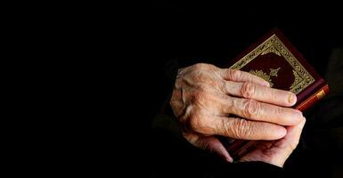 a mãos do Senior mulher em a Alcorão foto