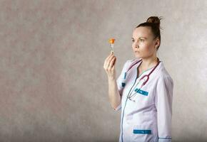 jovem fêmea médico vestido dentro uma branco médico uniforme mantém uma areia Assistir foto