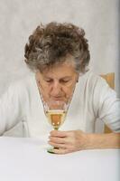 Senior mulher é sobre para beber uma vidro do branco vinho foto