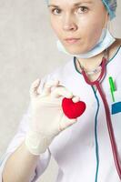 uma vermelho pelúcia coração dentro a mão do uma médico foto