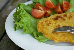 frango schnitzel com cereja tomates e verde salada folhas. foto