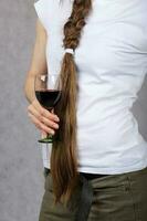 jovem senhora vestido dentro jeans mantém uma vidro do vermelho vinho. fechar-se foto