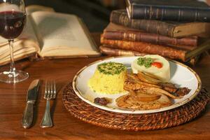 lindo carne de porco prato com farofa e purê. dentro a fundo velho livros foto