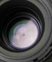 fechar acima do uma Câmera lente com uma azul e roxa reflexão. foto