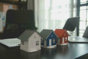 mãos de mulher feminina segurando modelo de casa, pequena casa de brinquedo branco em miniatura. sonho de seguro de propriedade hipotecária movendo-se para casa e conceito imobiliário foto