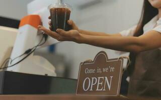 bem-vinda. abrir. barista, garçonete mulher girando aberto placa borda em vidro porta dentro moderno cafeteria café fazer compras pronto para serviço, cafeteria restaurante, varejo loja, pequeno o negócio proprietário, Comida e beber conceito foto