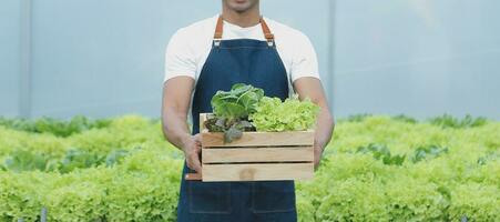 jovem ásia mulher e Senior homem agricultor trabalhando juntos dentro orgânico hidropônico salada vegetal Fazenda. moderno vegetal jardim proprietário usando digital tábua inspecionar qualidade do alface dentro estufa jardim. foto