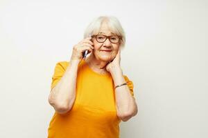 idosos mulher dentro uma amarelo camiseta posando comunicação de telefone luz fundo foto